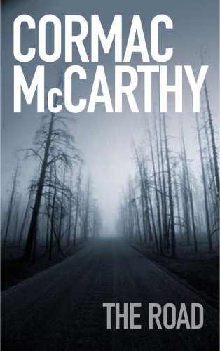 Book cover of 'The Road' by Cormac McCarthy, featuring the author's name in bold uppercase letters at the top and the title at the bottom, with a haunting image of a desolate road disappearing into a misty, barren forest.